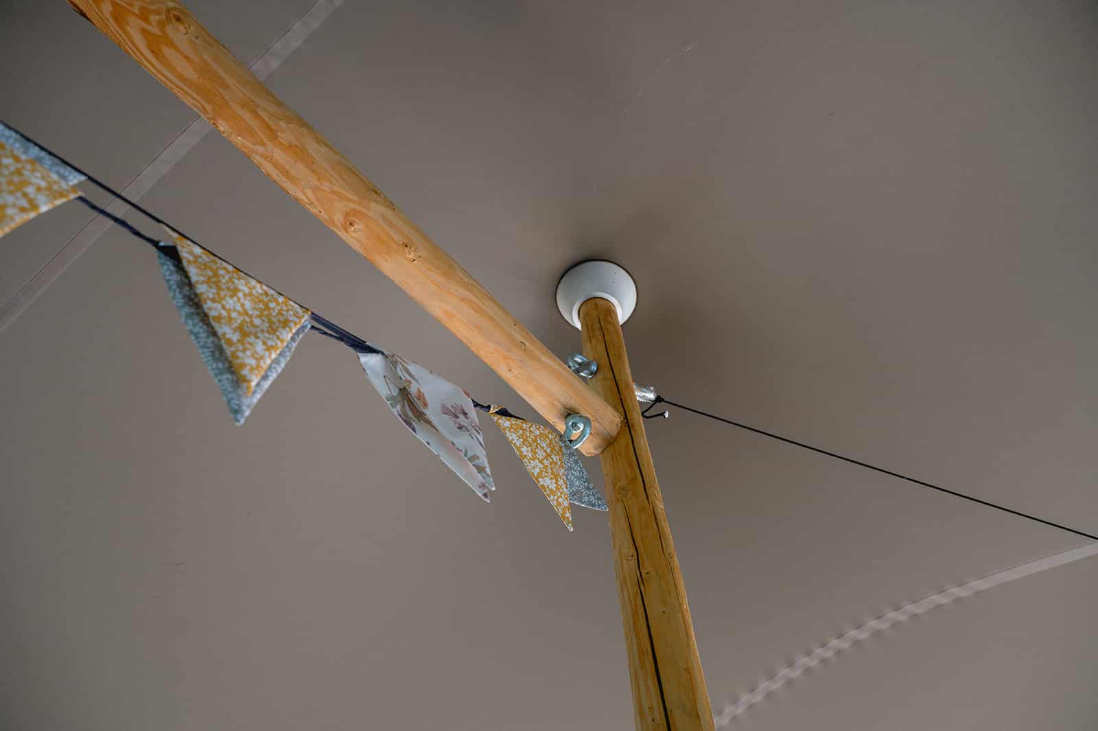 Mastkap op houten middelpaal in een taupe stretchtent