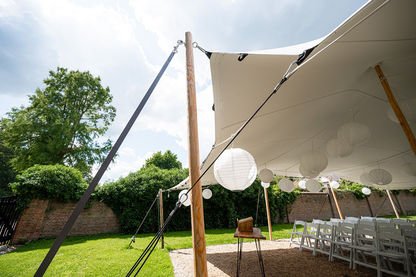 Witte stretchtent op een weiland waar de materialen zichtbaar zijn zoals de houten paal en spanband